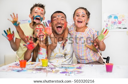 Portrait of a cute happy father with children painting and having fun. They are showing their hands painted in bright colors