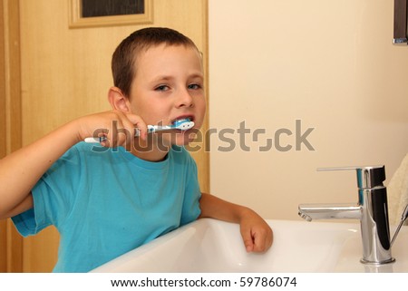 Six years old boy cleaning tooth in the bathroom.
