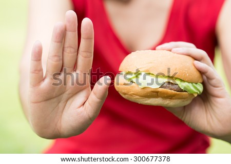 Woman making stop sign with hamburger