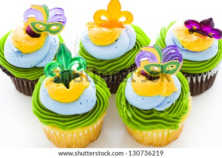 Fancy cupcakes decorated with leaf and mask for Mardi Gras party.