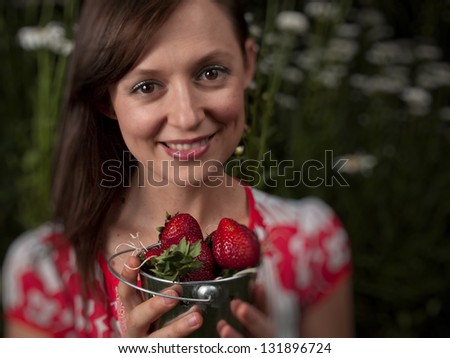Portrait of a smiling young woman holding strawberries.