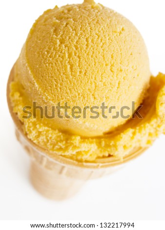 Scoop of gourmet pumpkin gelato in cake cone on white background.