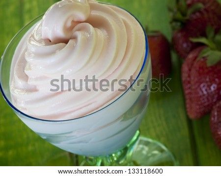 Cup of strawberry frozen yogurt or soft serve ice cream with fresh fruit.