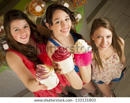 Teenage girls eating frozen soft serve yogurt.