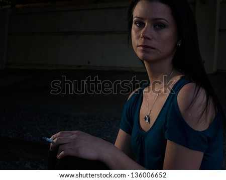 Real young woman smokes on railroad trucks.