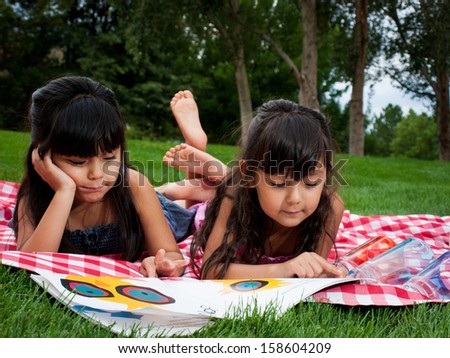Two sisters reading book in the park.