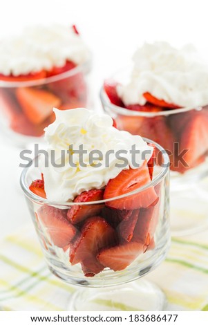 Fresh strawberries with whippes in glass bowls cream for dessert.