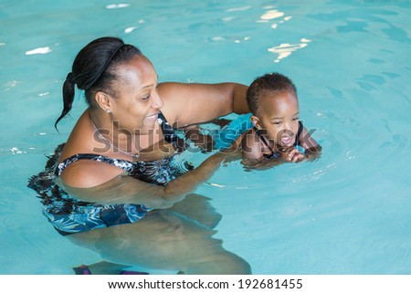 Cute baby girl learning how to swim in indoor pool.