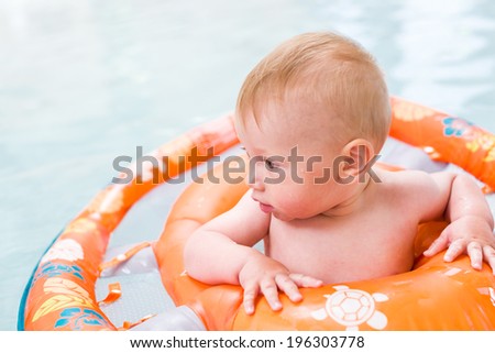 Baby playing in the water at indoor wsimming pool.