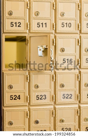 Rows of gold post office boxes with one open mail box.