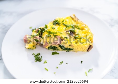 Slice of spinach and ham frittata on a white dinner plate. Foto d'archivio © 