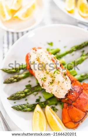 Sering garlic lobster tails with steamed asparagus and lemon wedges on a white plate. Imagine de stoc © 