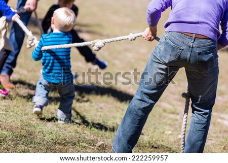 Two families playing vintage rope pulling game in the park.