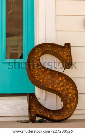 Large letter S made from rusted metal on the front poarch.