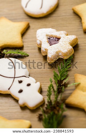 Sugar cookies in shape of snowman, stars, and christmas tree on wood table.