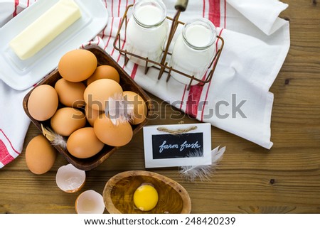 Fresh farm eggs, milk and butter on wood table.