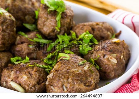 Serving large Italian meatballs in a white serving dish for dinner.