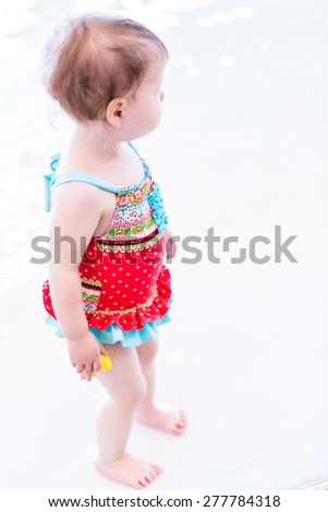 Cute toddler girl enjoying playing in the water in indoor swimming pool.