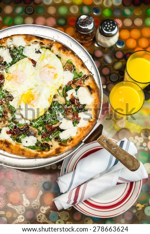 Fresh breakfast pizza with three farm fresh eggs in Italian restaurant.