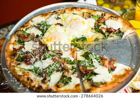 Fresh breakfast pizza with three farm fresh eggs in Italian restaurant.