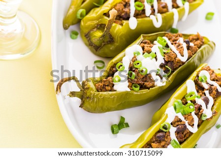 Chipotle beef & bean stuffed chile peppers garnished with sour cream and scallions.