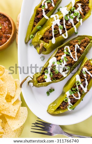 Chipotle beef & bean stuffed chili peppers garnished with sour cream and scallions.