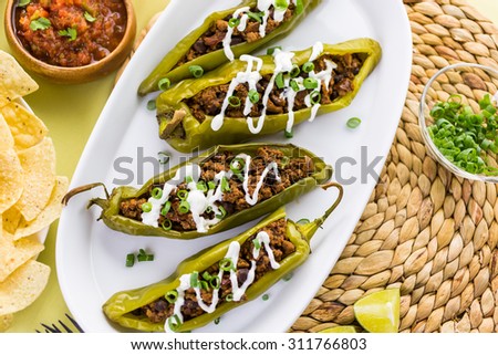 Chipotle beef & bean stuffed chili peppers garnished with sour cream and scallions.