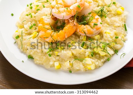 Homemade corn risotto with roasted shrimp on dining table.