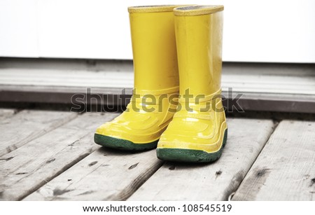 Kids yellow boots on the wooden deck entrance