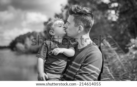 father and son giving each other a kiss in black and white