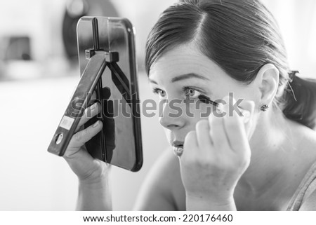 beautiful woman looking in the mirror bringing up her makeup