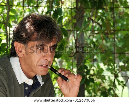 Close up of a satisfied smoker of electronic cigarette in dim light