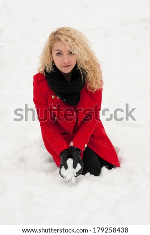 Joyful girl in red coat playing with snow