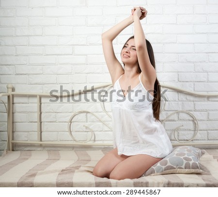 beautiful graceful girl on the bed stretches gladly in morning