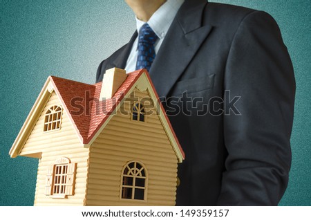 Business man with house model on hand- real estate concept.