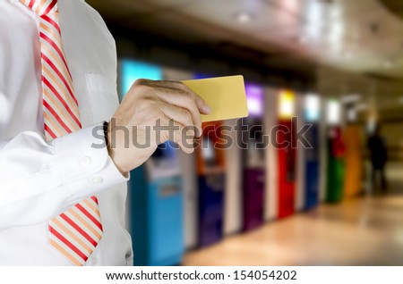 Business man showing a blank gold credit card, ATM Machine background