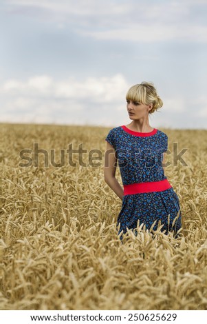 Portrait of a young woman on the background of a field of wheat on a clear day