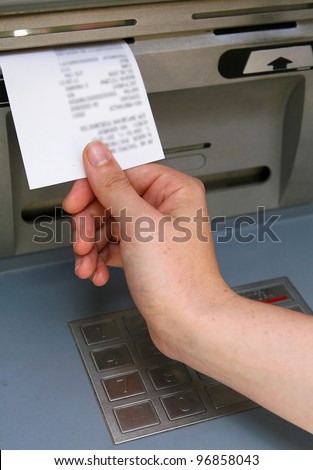 A hand taking a receipt of an Automated Teller Machine, information on the receipt is blurred by photo-editing software.