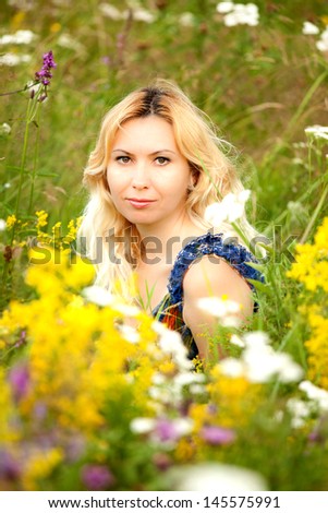 Beautiful young woman in a field of flowers, smiling, feeling positive and peaceful