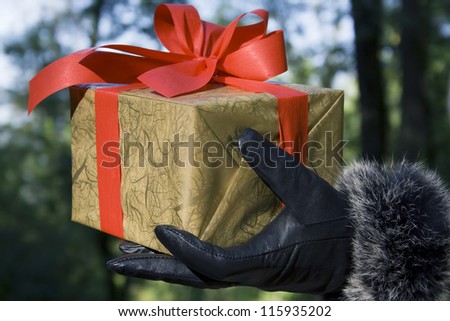 Hand in glove holding - giving a gift box