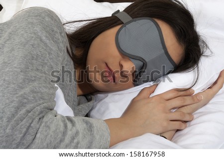 Young woman taking a nap during the day with sleeping mask -  Lies with sleeping mask in the bed.
