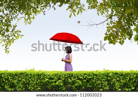 shrubs fence and young woman holding a red umbrella