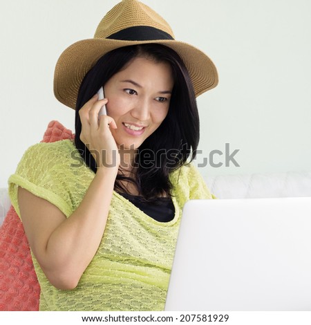 Happy young beautiful woman using a laptop and a smartphone on bed indoor.