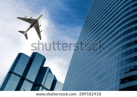 Airplane flying above glass office buildings. Wide lens effect.