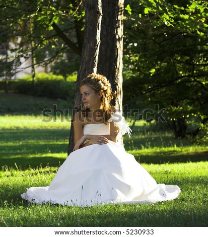 Wedding concept. Bride portrait in wedding dress sitting in park