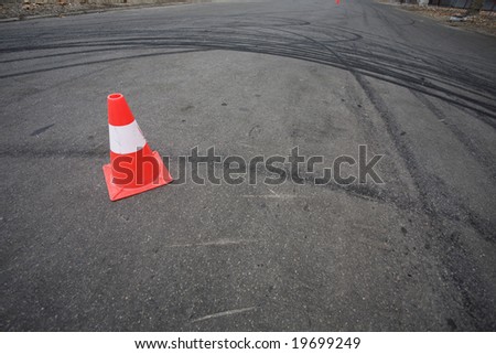 Orange traffic cone and round car drift skid marks