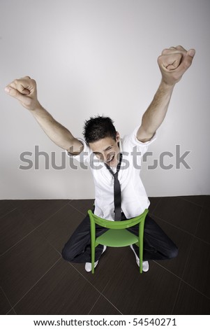Young man with arms in the air, sitting on a chair cheering