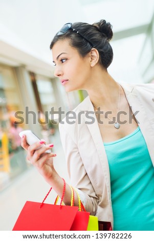 Shopping time, woman at shopping mall, looking at windows, holding cell phone