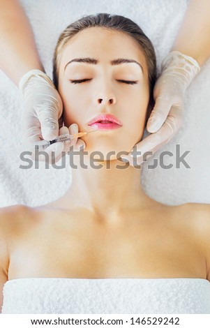 Woman face and beautician hand with syringe