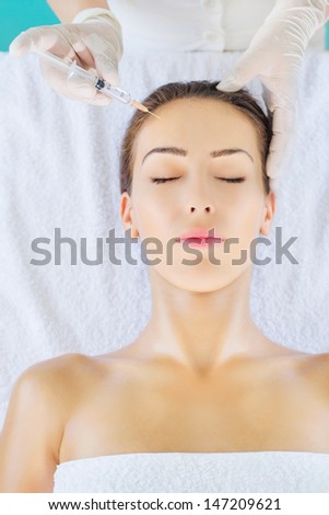 Woman face and beautician hand with syringe